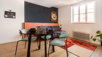 Een moderne eetruimte met een ronde tafel, vier stoelen en een rood-beige vloerkleed.