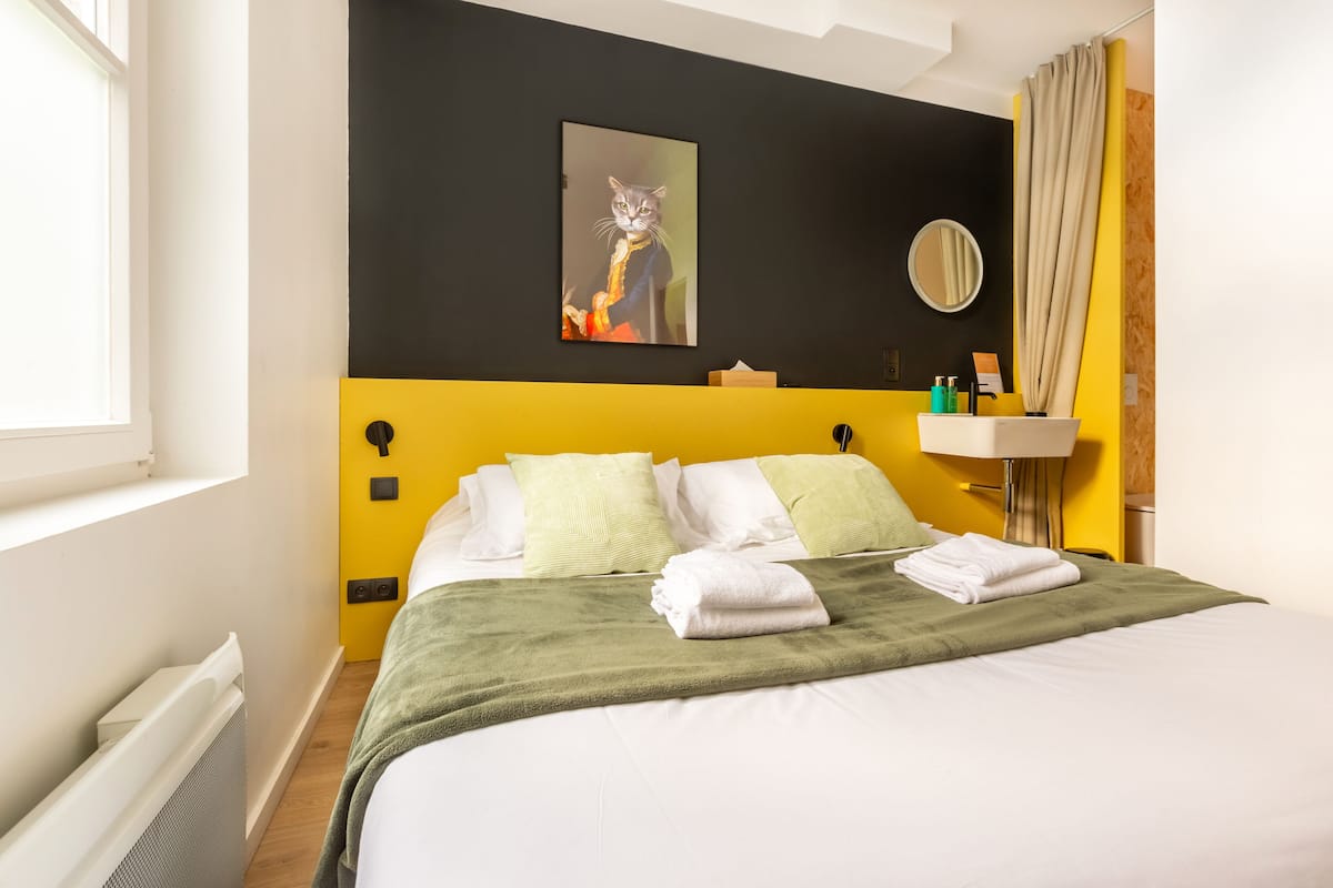 Une chambre d’hôtel comprenant un lit, un tableau, un miroir et une salle de bain.