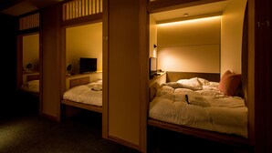 A hotel room with three single beds, each with a wooden headboard and a bedside table. - Hatagoya Jyozankei Shoten - Hostel (Sapporo)