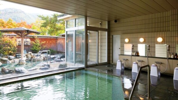 A modern indoor pool with clear glass walls, a stone pathway, and a view of autumn trees. - Hatagoya Jyozankei Shoten - Hostel (Sapporo)