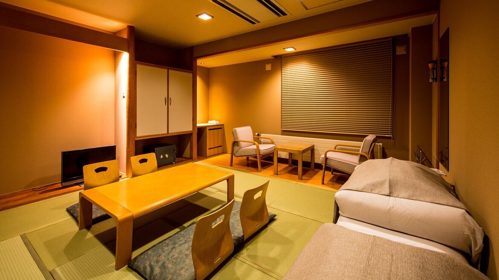 Um quarto japonês tradicional com tatames, uma mesa baixa, cadeiras, um sofá e portas deslizantes.