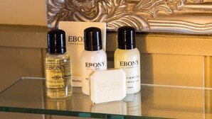 Une étagère en verre sur laquelle sont posées trois bouteilles de produits capillaires de la marque Ebonyl London et une boîte blanche.