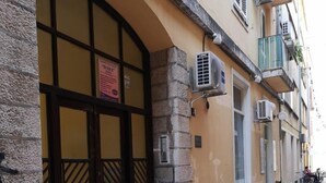 Un bâtiment doté d’une façade en pierre, d’une grande entrée en arc de cercle et de plusieurs unités de climatisation.