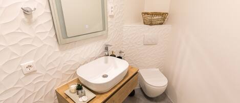 A bathroom with a white sink, wooden vanity, and a white toilet.