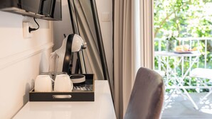 Une chambre d’hôtel équipée d’un bureau, d’une chaise, d’un plateau avec des tasses et une télécommande, et offrant une vue sur l’extérieur.