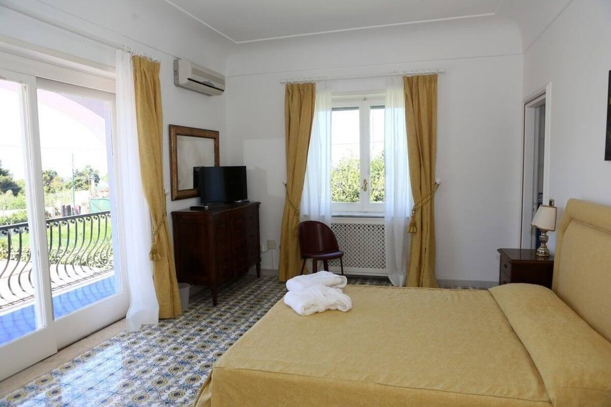 Una habitación de hotel con una cama, televisor, escritorio y una silla.