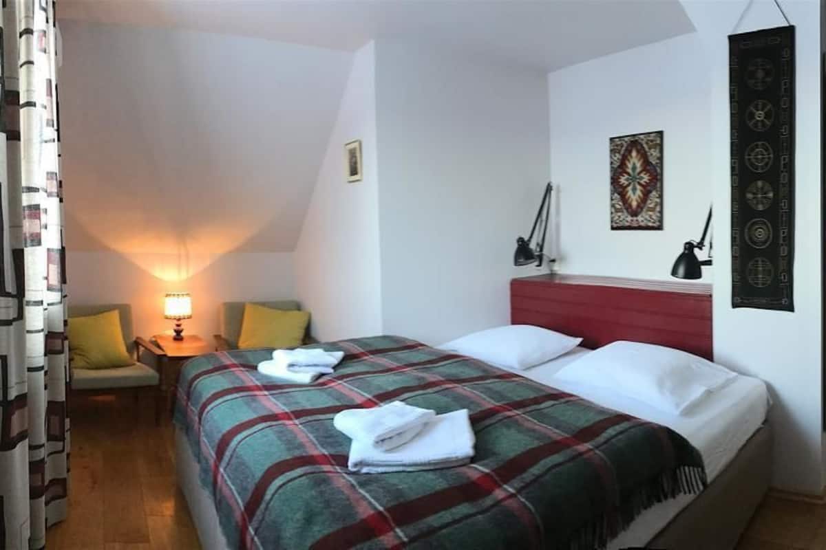 A bedroom with a bed, a nightstand, a lamp, and a wall decoration.