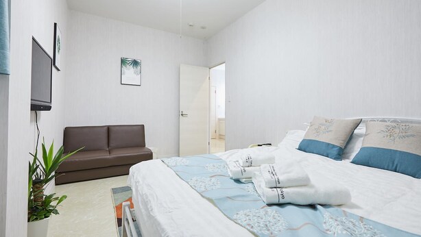 Una habitación de hotel con una cama, un sofá, un televisor y una puerta.