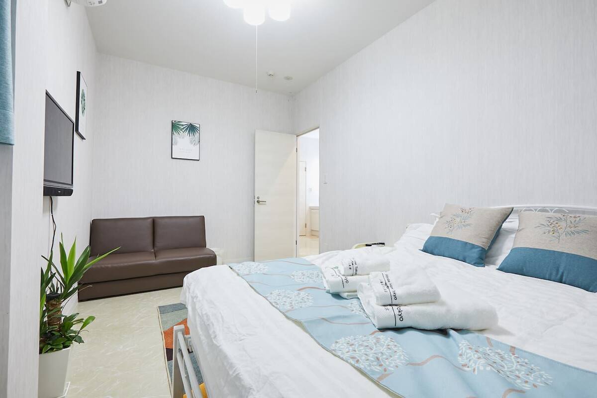 Una habitación de hotel con una cama, un sofá, un televisor y una puerta.
