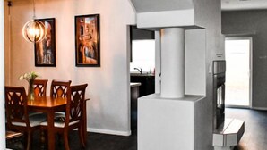 A modern kitchen with a central island, a dining area with a wooden table and chairs, and a large arched doorway leading to another room. - Advantage Court (Las Vegas)