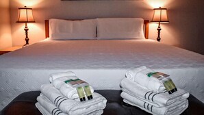 A hotel room with a large bed, two bedside lamps, and towels with toiletries on the bed. - Advantage Court (Las Vegas)