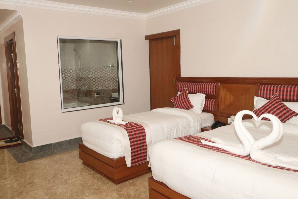 A hotel room with two beds, a large window, and a wooden headboard.