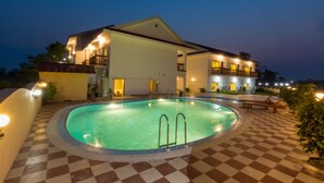 A hotel with a swimming pool, checkered flooring, and multiple balconies. - Hotel Earth Light (Sauraha)