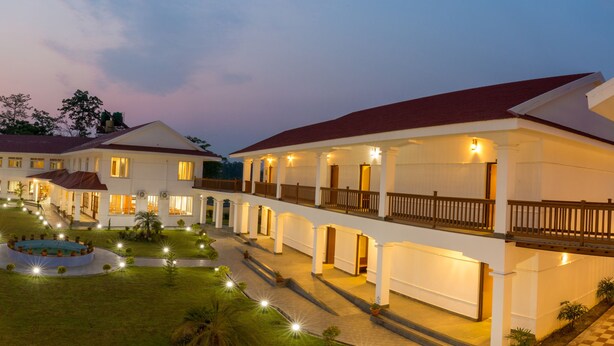 A hotel courtyard with multiple buildings, a central pool, and well-lit pathways. - Hotel Earth Light (Sauraha)