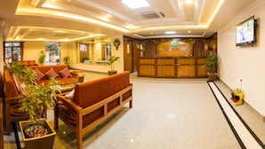 A hotel lobby with a reception desk, sofas, and potted plants. - Hotel Earth Light (Sauraha)