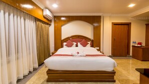 A hotel room with a large bed, wooden headboard, and a wooden wardrobe. - Hotel Earth Light (Sauraha)