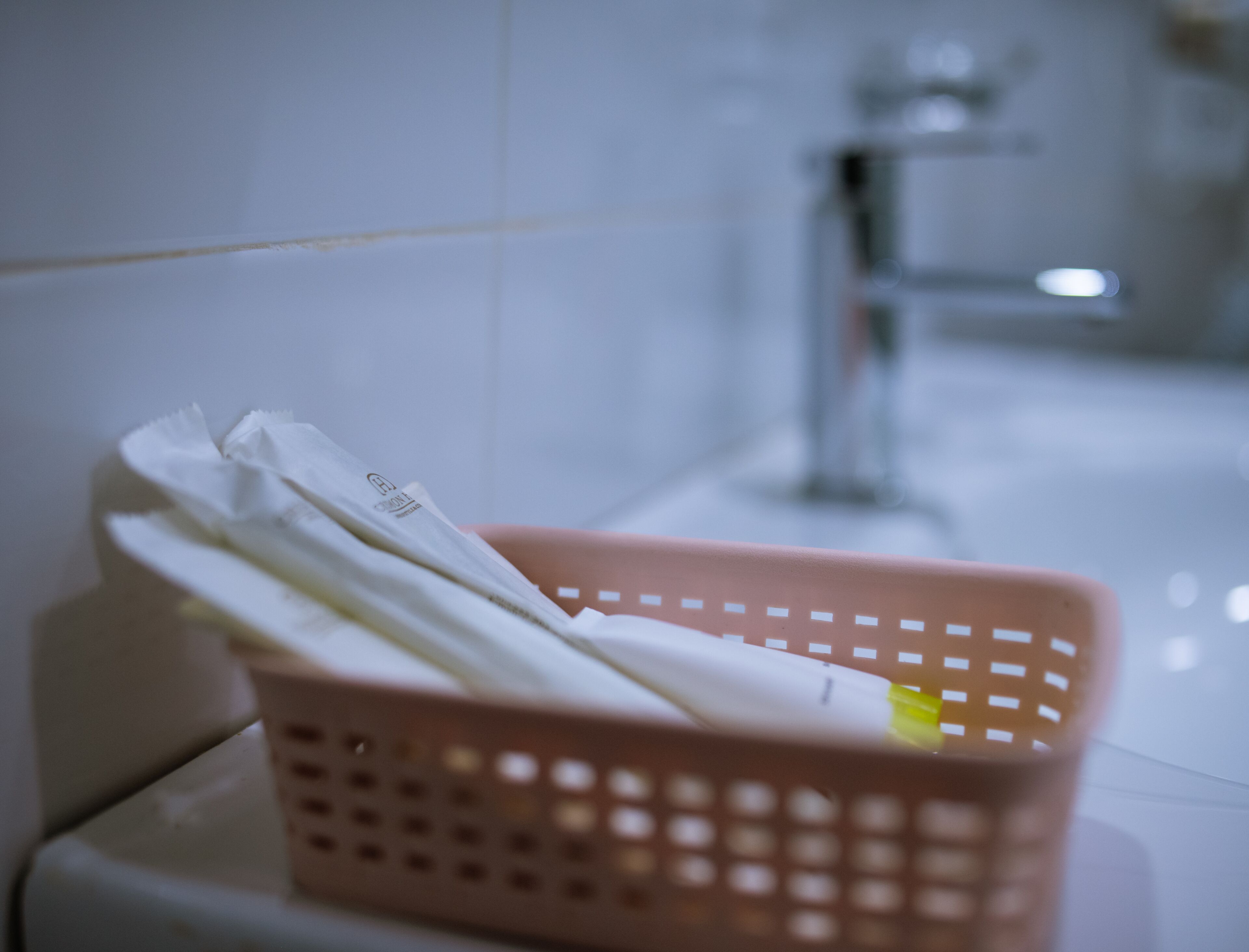 A bathroom with a pink basket containing white towels and a yellow object.