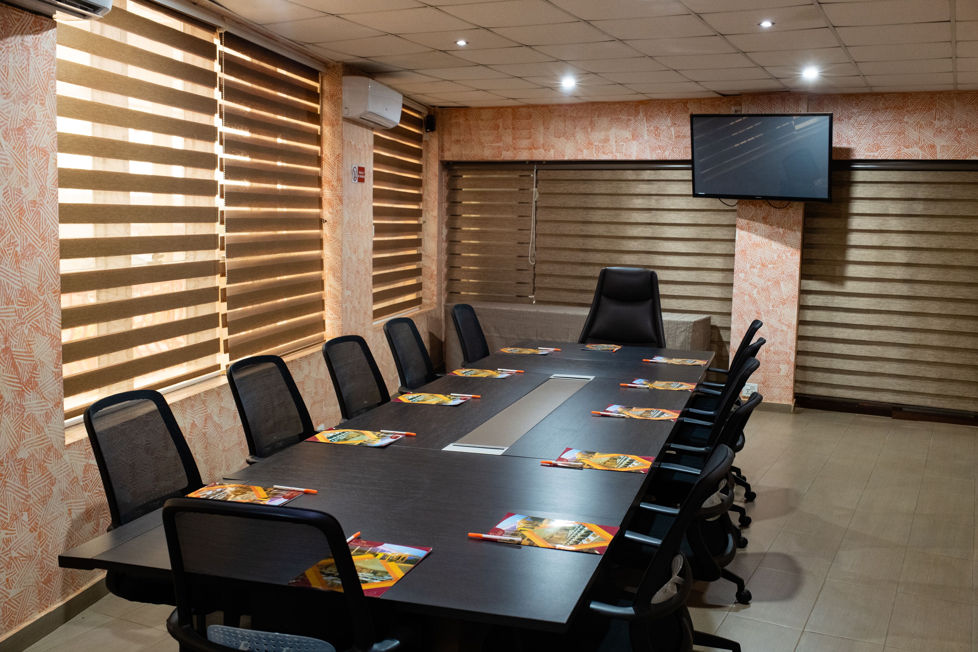 A conference room with a long table, chairs, a TV, and patterned walls.