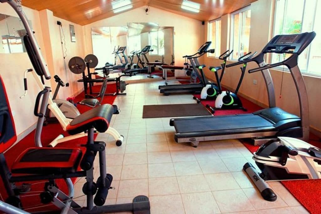 Un gimnasio con cintas de correr, bicicletas estáticas y máquinas de pesas.