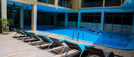 A swimming pool with lounge chairs and a covered area.