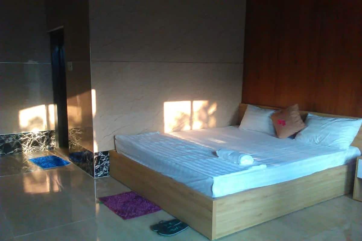Une chambre à coucher avec un lit en bois, un tapis bleu et violet, et une porte en bois.