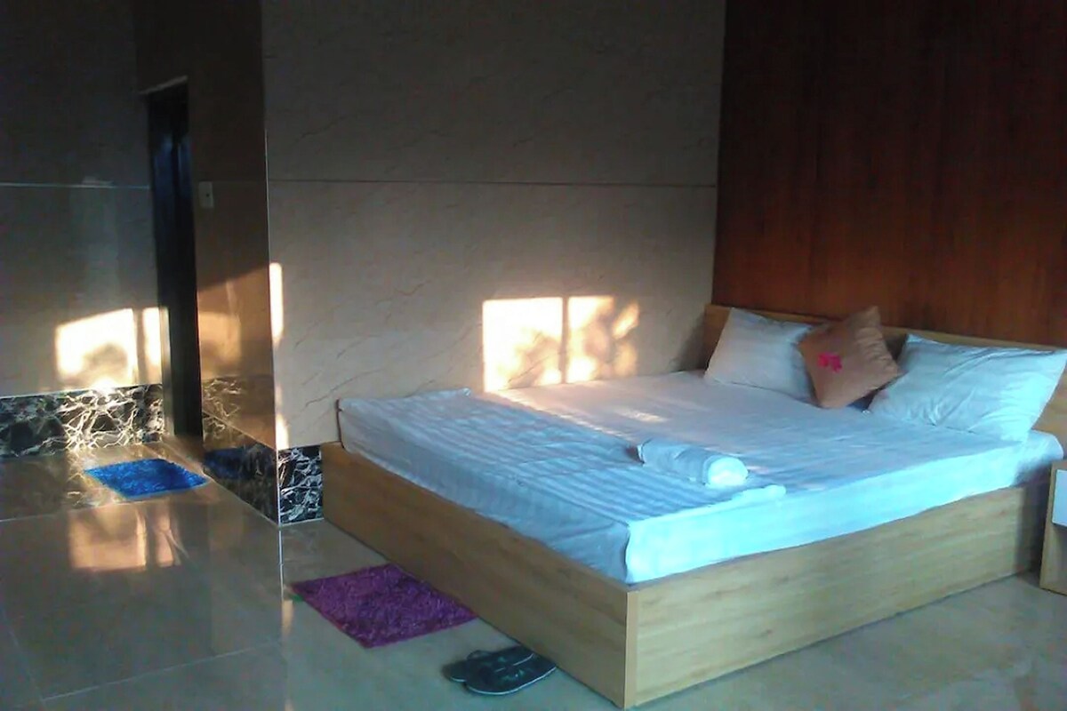 Ein Schlafzimmer mit einem hölzernen Bett, einem kleinen Teppich und einem Paar Hausschuhen auf dem Boden.