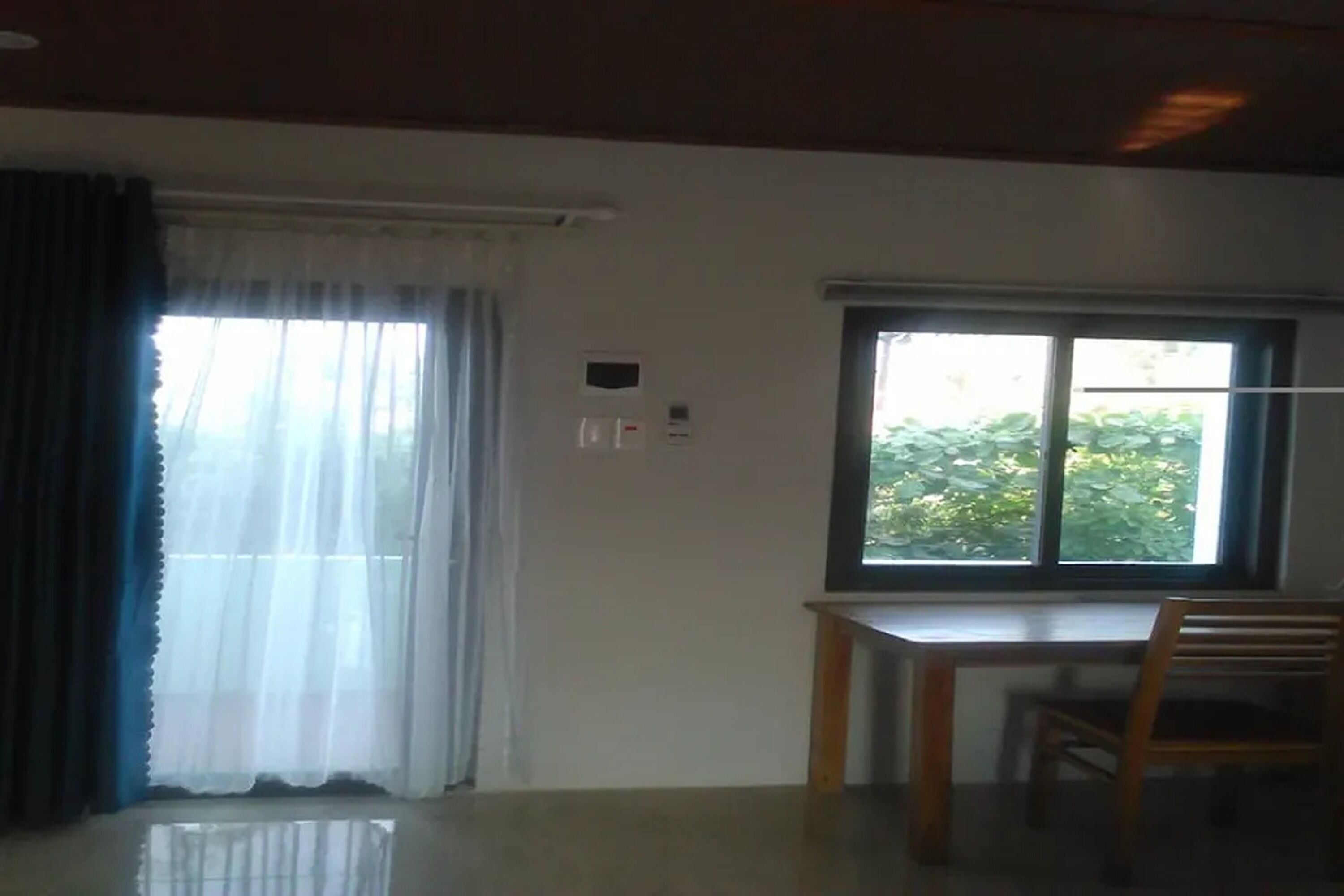 A room with a large window, a wooden table, and a chair.