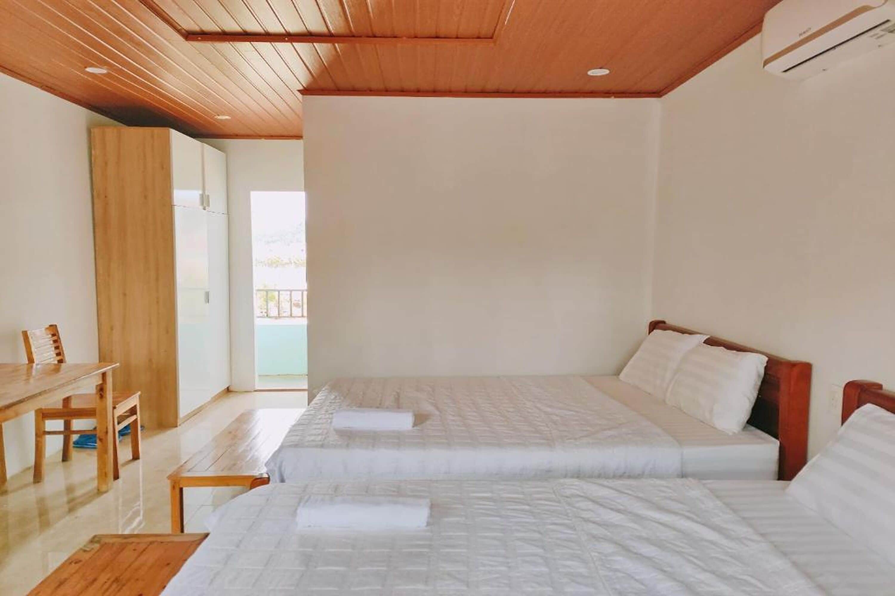 Een hotelkamer met twee bedden, een houten bureau en uitzicht op buiten.