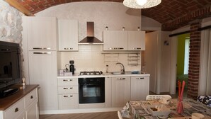A compact kitchen with white cabinets, a built-in oven, and a dining area with a table set for two.