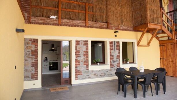 A dining area with a table and chairs, a staircase, and a view of the kitchen through an open door.