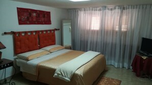 A hotel room with a bed, a desk, a television, and a window with curtains. - SEGESTA - Le Bouquet (Salemi)