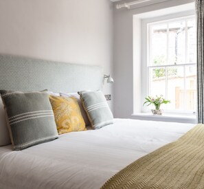 A bedroom with a bed, pillows, a bedside lamp, and a window with a view of the outside. - The Porlock Weir Hotel (Minehead)