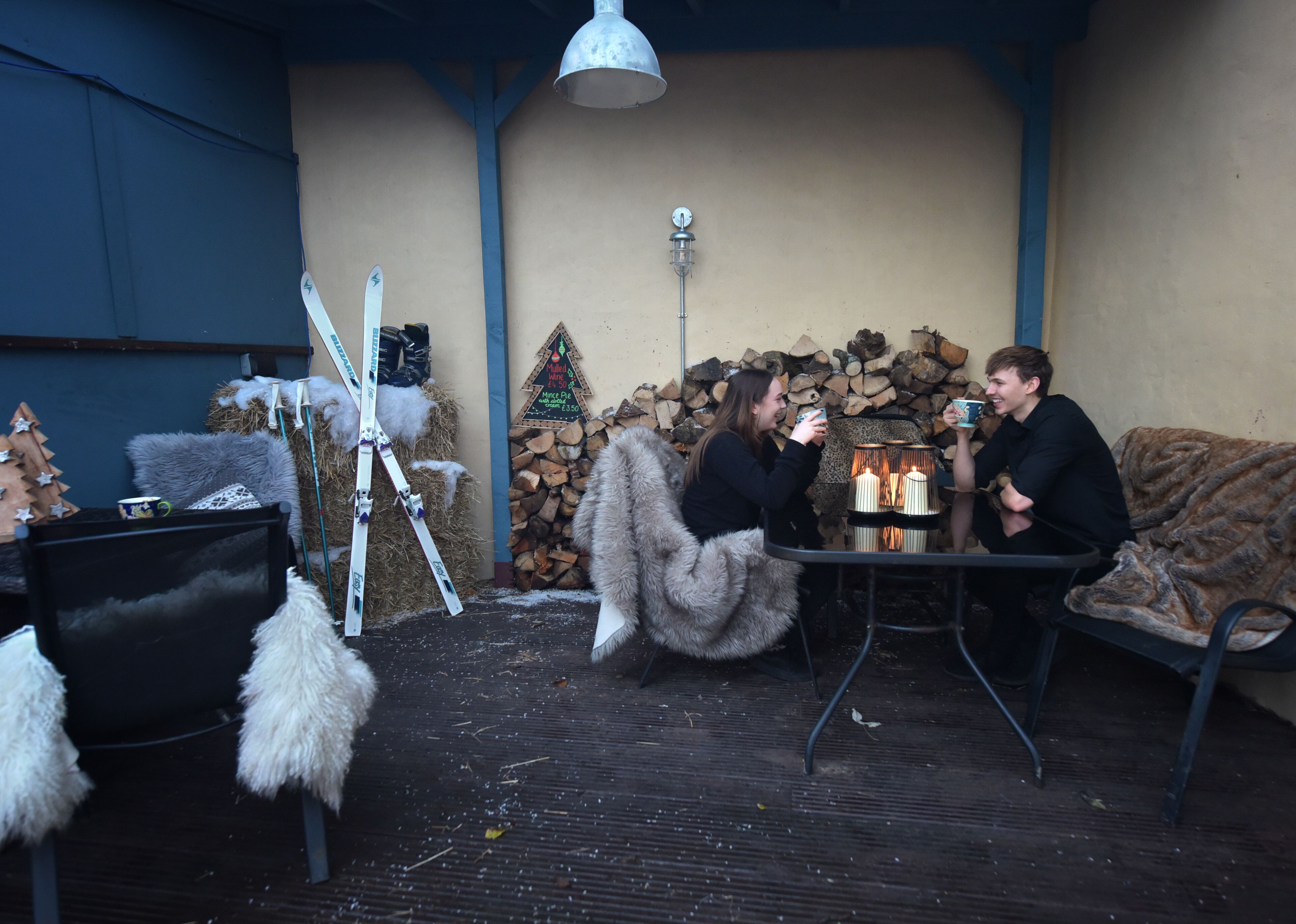 A cozy outdoor seating area with a fireplace, a Christmas tree, and a ski rack.