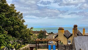 Une propriété située sur la côte, dotée d’une pelouse verdoyante, d’une pergola en bois et offrant une vue sur la mer.