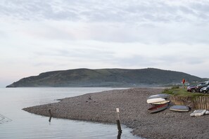 A rocky shoreline with boats and cars parked near the water.