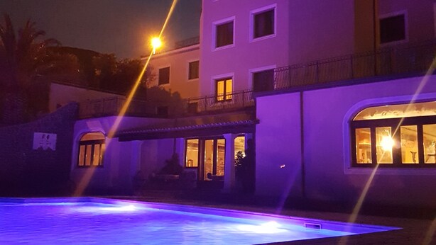 Un edificio de varios pisos con zona de piscina, que presenta un techo plano y un balcón en el piso superior.