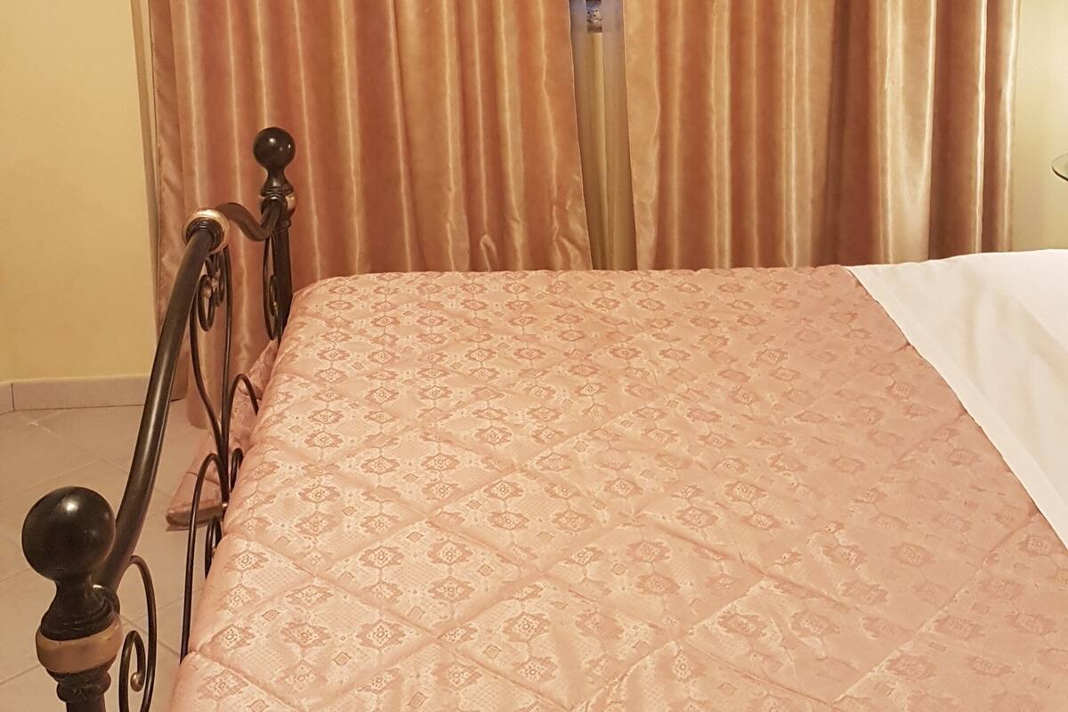 A room with a bed, curtains, and a window.