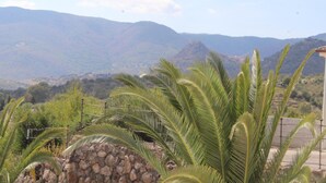 Un paisaje montañoso con un muro de piedra y palmeras en primer plano.