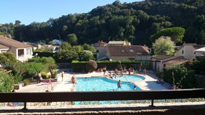 Ein Poolbereich mit freiem Blick auf die umliegenden Wohnhäuser und eine hügelige Landschaft im Hintergrund.