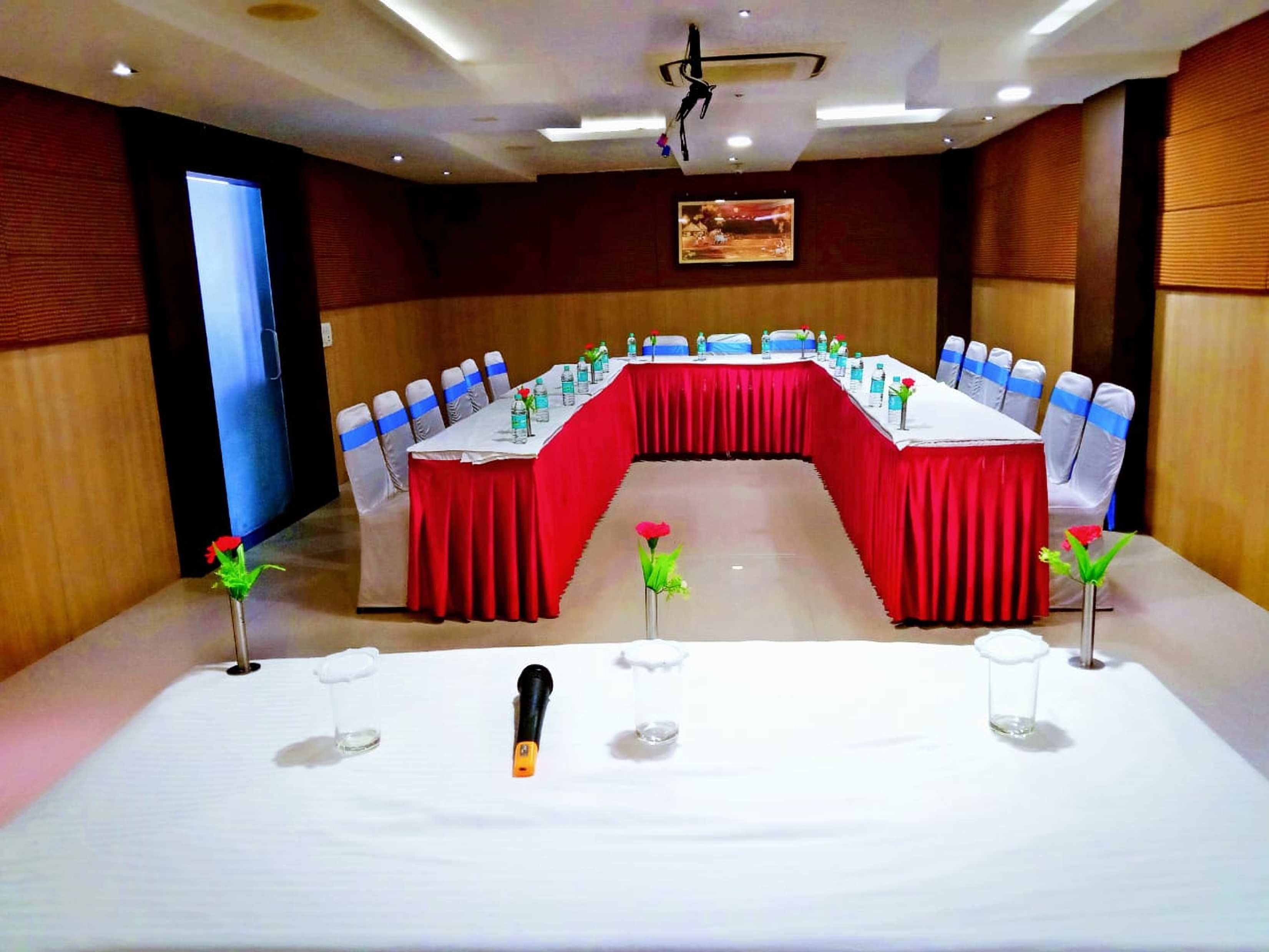 A conference room with a long table, red tablecloth, and blue chair sashes.