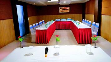 A conference room with a long table, red tablecloth, and blue chair sashes.