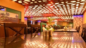 A dining area with a patterned ceiling, wooden chairs, and a table with a vase of flowers. - HOTEL ROCK FORT VIEW by Park Elanza (Tiruchirappalli)