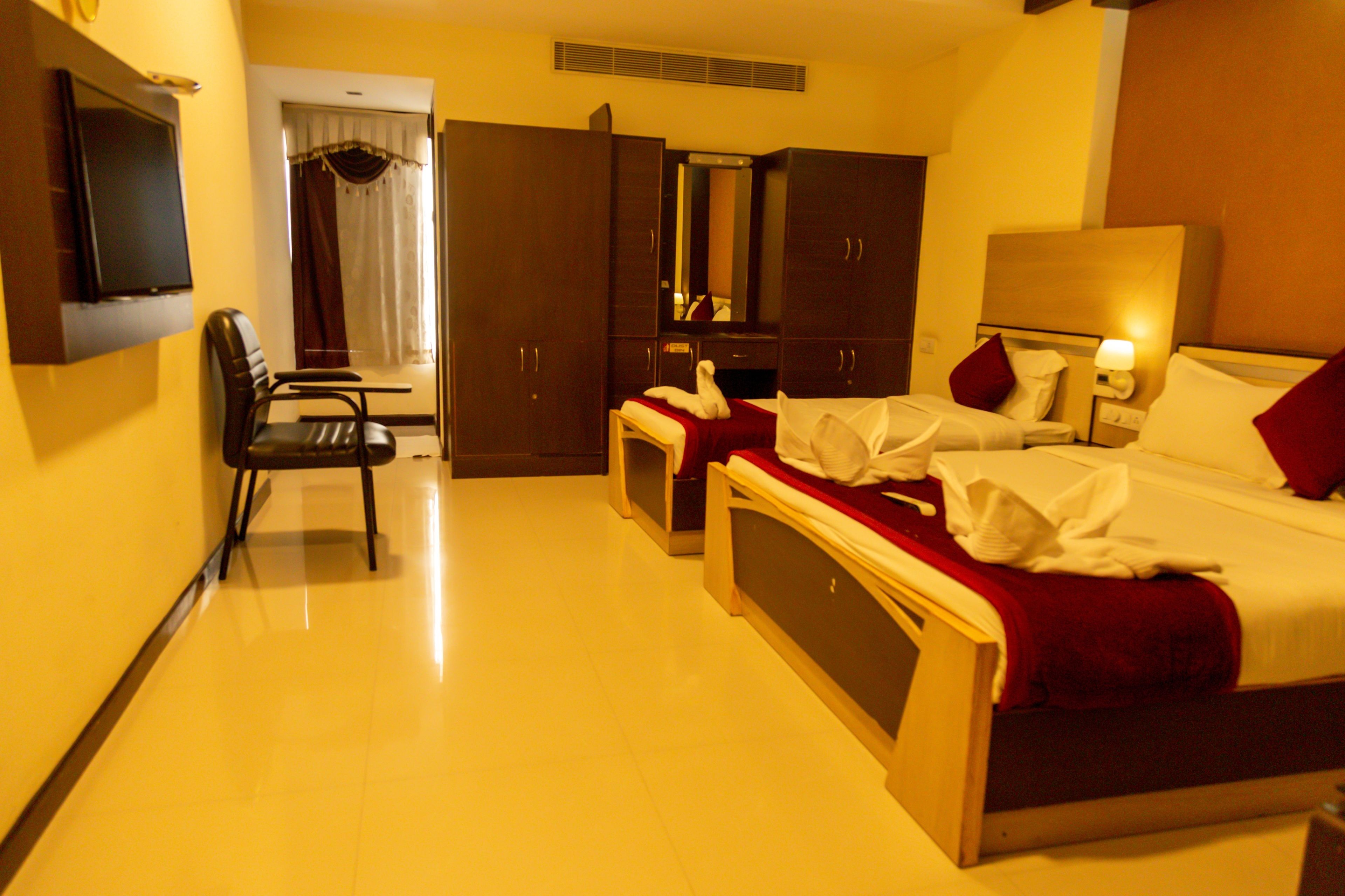 A hotel room with a bed, a chair, a desk, a TV, and a wardrobe.
