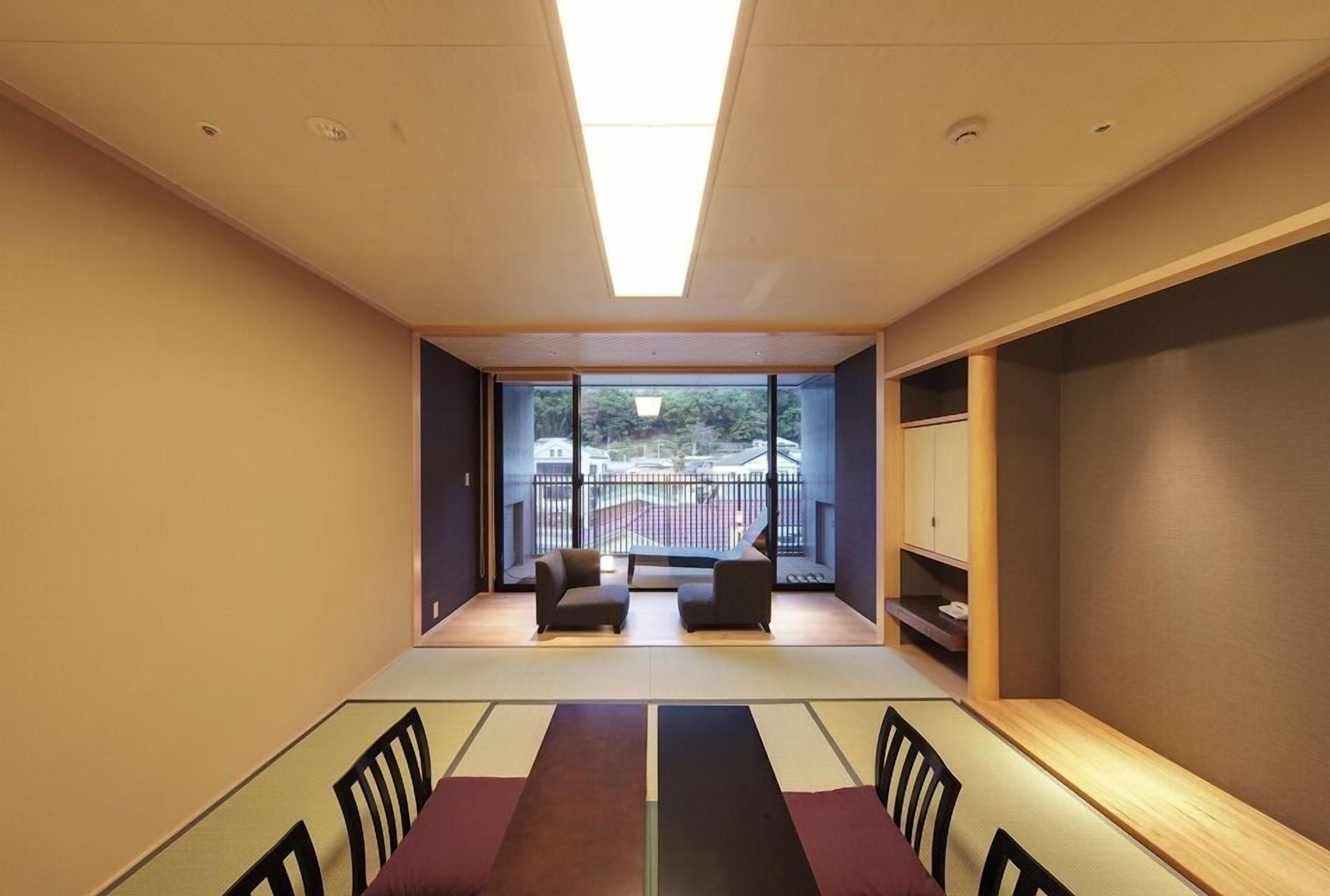 Una habitación moderna con un ventanal grande, un sofá, una mesa de comedor y un armario.