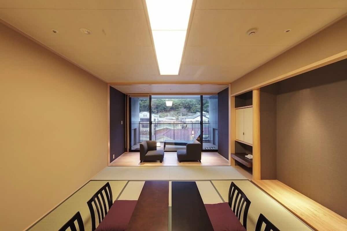 A modern room with a large window, a sofa, a dining table, and a cabinet.