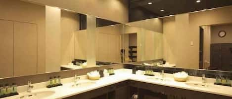 A modern bathroom with three sinks, large mirrors, and a clock on the wall.
