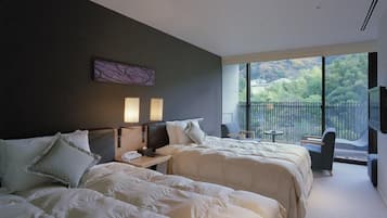 Ein Hotelzimmer mit zwei Betten, einem Balkon mit Blick und einem kleinen Tisch mit Stühlen.