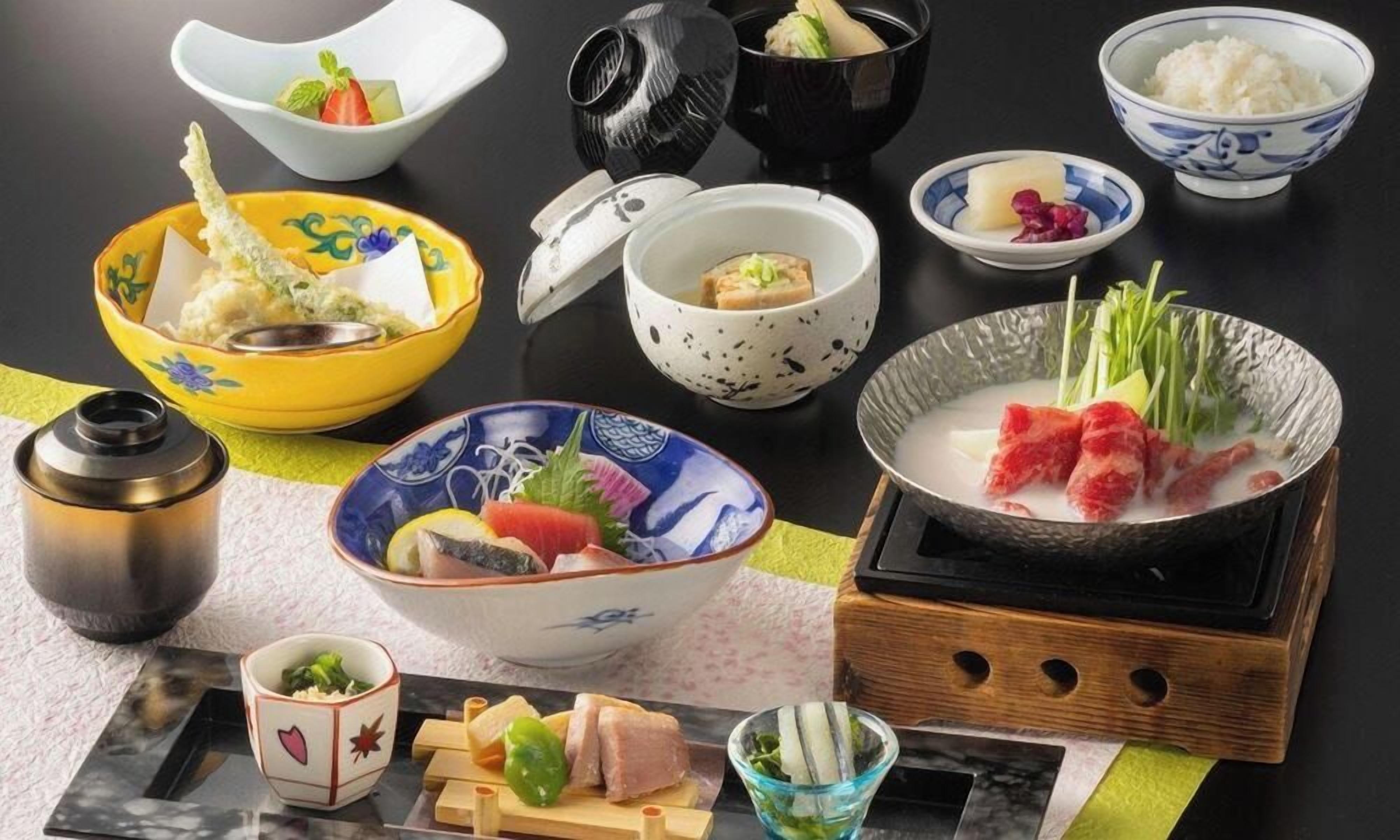 Verschiedene japanische Gerichte, darunter Sushi, Sashimi und Reisgerichte, sind auf einem Tisch angerichtet.