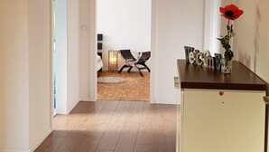 A hallway with a wooden floor, a white door on the left, and a wooden cabinet on the right.
