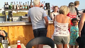 Een bar met een houten toonbank, flessen, glazen en een speaker.